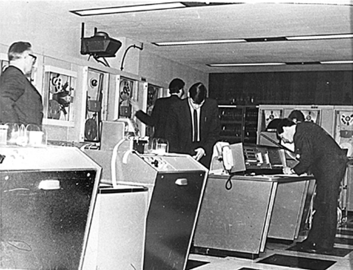 LEO III / 7: J. Lyons.<br /> Peter Bird at the Ops console<br />Left is Arthur Noon, Head of the Computer Dept